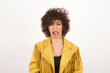 Vücut dili. Gri duvara karşı poz veren, suratını asan, bir şeyden tiksindiğini gösteren, stresli, güzel bir kız..