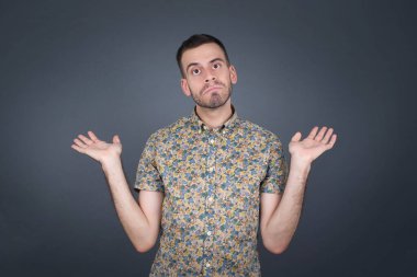 Kafası karışmış, kolları açık, omuzlarını silkip 