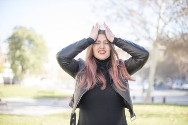 Parkta elleri başının üstünde genç ve güzel bir kadın.