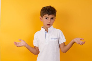 Yakışıklı çocuğun sarı duvara karşı kafası karışık.  