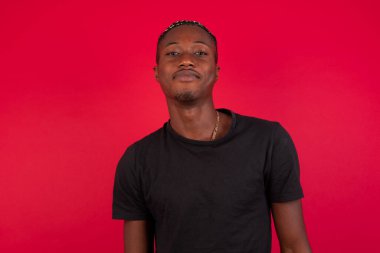 Stüdyoda, siyah kıvırcık saçlı yakışıklı Afro-Amerikan erkek modelinin, sevimli bir gülümsemeyle kameraya bakarken, boş fotokopi duvarına karşı poz verirken ki görüntülerini kapatın. 