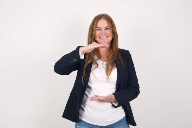  Güzel orta yaşlı kadın duvarın arkasında bir şey gösteriyor..  