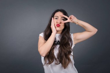 Güzel bir kadın jesti. Gri arkaplanda duruyor. 