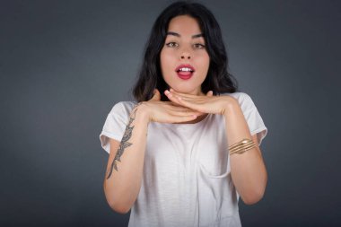 Stüdyoda oynaşan ve elleriyle çeneye dokunan bir kadın. 