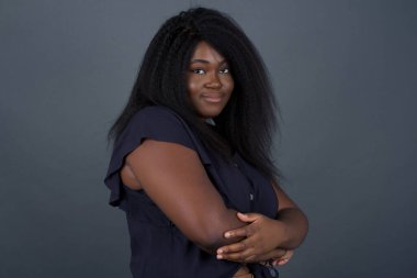 İçerde kolları bağlı duran neşeli Afrikalı Amerikalı kadın görüntüsü. Kameraya bakıp gülümsüyor.. 