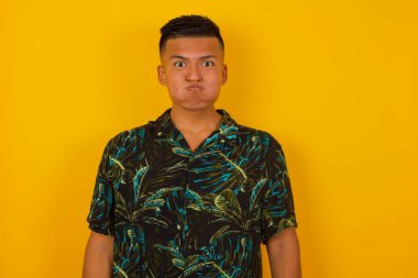 Yakışıklı genç İspanyol adam komik suratıyla yanaklarını şişiriyor. Havayla şişmiş ağız, çılgın bir ifade..