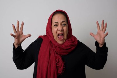 Çığlık, nefret, öfke. Ağlayan duygusal sinirli olgun Müslüman kadın stüdyo arka planında çığlık atıyor.. 
