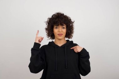 Pozitif sevinçli dişi der ki: Vay be, ne kadar heyecan verici, hayret verici bir ifade, bir şey ifade ediyor. Neşeli genç bayan bir şeyler gösteriyor. Bir eli göğsünde ve diğer eliyle işaret ediyor..