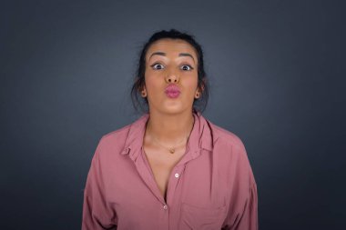 Hoş görünümlü genç bir kadın birini öpecek gibi dudaklarını tutuyor, mutlu bir ifadesi var, suratsız surat. Dışarıda dikiliyorum. Güzellik konsepti. 