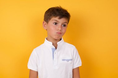 Yakışıklı çocuk sarı duvara karşı üzgün.  
