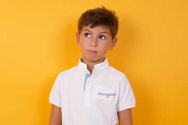 Tatlı çocuk sarı duvara bakıyor.  