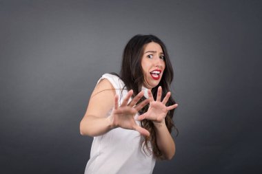 Güzel kadın korkuyor Gri arka planda duruyor. 