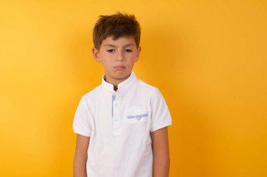 Yakışıklı çocuk sarı duvara karşı üzgün.  