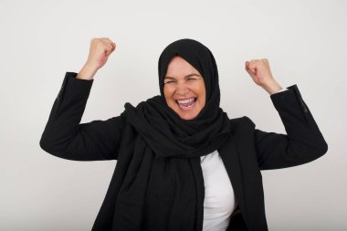 Evet, ben kazandım. Çekici, keyifli, orta yaşlı, tesettürlü Müslüman kadının portresi zafer ve zaferle yumruğunu kaldırıyor. Mutluluktan sırıtarak başarı elde ediyor..