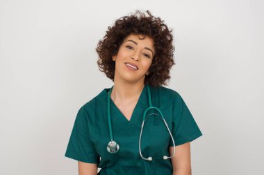 Güzel görünümlü beyaz kadın doktorun yatay portresi. Sağlık üniforması giyiyor ve kameraya mutlu bir şekilde bakıyor..