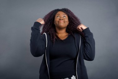 Heyecanlı Afro-Amerikan kadın, sıradan giyinmiş. Kazanan, yumruklarını büyük bir mutlulukla kaldırıyor. Maçı kazandıktan sonra keyfi yerinde. Genç şampiyon hedeflerine ulaştığına seviniyor. Zafer ve zafer kavramı.