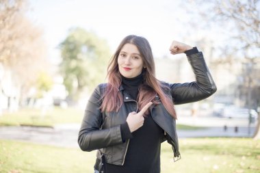 Parkta kaslarını gösteren genç ve güzel bir kadın.