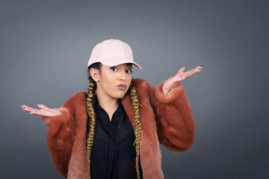 Güzel bir kadın ifadeden şüphe eder, şaşırır ve şaşırır, belirsiz bir gelecek omuzlarını silker, gri duvara karşı durur..