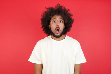 Kızıl duvara karşı ağzı açık afro saçlı genç bir adam.   
