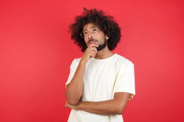 Kızıl duvara karşı düşünen afro saçlı genç bir adam.   