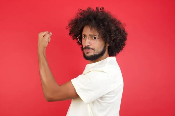 Giovane Uomo Con Capelli Afro Mostrando Muscolo Contro Muro Rosso — Foto Stock