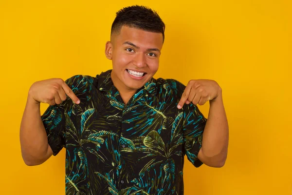 Çekici, duygusal bir İspanyol erkeğin tişörtünü göstermesi ya da sevinçle gülümsemesi ve arka planda olumlu duygular ifade etmesi. Çocuk çok antrenman yaptı, o da kaslarını göstermek istiyor.