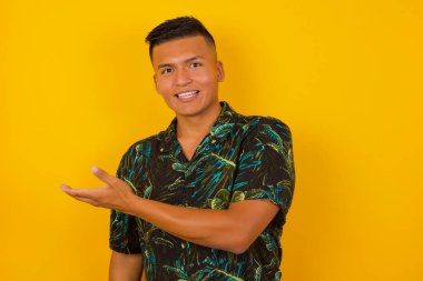 Pozitif memnun adam ifadeyi şaşırttı, boş alanda bir şey gösteriyor, izole edilmiş sarı arka plan üzerinde açık elle. Reklam kavramı.