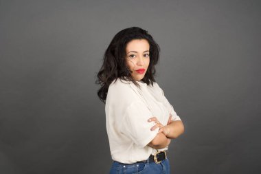 Gayri resmi giyinmiş güzel esmer kadın. Gri arkaplanda duruyor. 