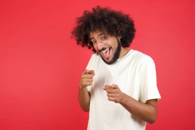 Kızıl duvarı işaret eden afro saçlı genç adam.   