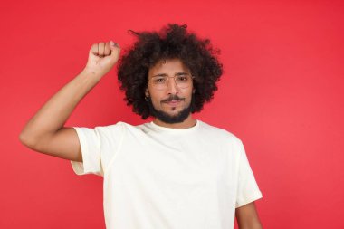 Kızıl duvarda yumruğunu gösteren afro saçlı genç adam. 