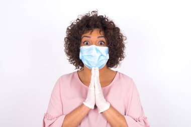 Yüz maskesi takan kadın ve günlük kıyafet çantası beyaz stüdyo arka planında izole edilmiş.