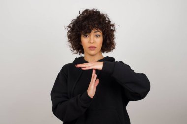 Genç ve güzel bir kız yorgun ve sıkılmış, mola veriyor, iş stresi ve zaman kavramı yüzünden durması gerekiyor. Gri duvara yaslanarak.