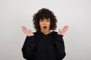 Sürpriz konsept. Kapüşonlu, hayretler içinde güzel bir kadının portresi. İnanamamasına şaşırmış, ağzı açık, yüzüne yakın, saçları örgülü. Olumlu duygu yüz ifadesi vücut dili.