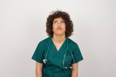 Hüzünlü, sıkkın, güzel Arap doktor kadın kaşlarını çatmış, kaşlarını çatmış yukarı bakıyor, çok fazla konuşmaktan rahatsız oluyor, yorgun ve gitmek istiyor. Kızgın somurtkan kadın ayakta duruyor 