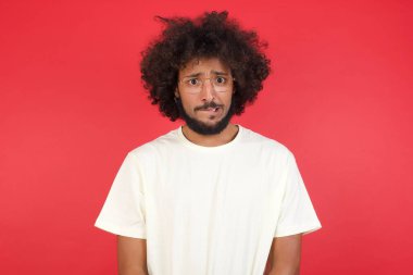 Afro saçlı genç adam kırmızı duvara karşı üzgün. 
