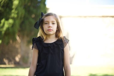 Neşeli genç bir kızın belini kaldırıp kameraya bakması, düşünmesi ya da merak etmesi. İki kolunu da indir, tarafsız yüz ifadesi..