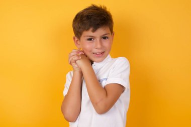 Sarı duvara yaslanmış sevimli çocuk.  