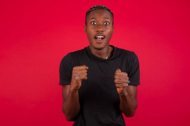 İnsan yüzü ifadeleri ve duyguları. Paniğe kapılmış genç Afro-Amerikan bir adamın portresi. Ellerini yüzünün yanında, ağzı açık bir şekilde tutuyor. Umutsuzluk ve şok içindeki bir erkek