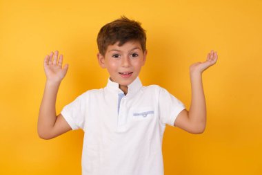 Sarı duvara yaslanmış sevimli çocuk.  