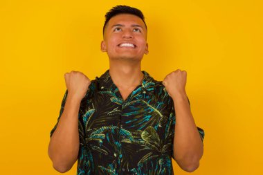 Heyecanlı, yakışıklı, İspanyol asıllı erkek yumruklarını büyük bir mutlulukla kaldırıyor. Maçı kazandıktan sonra keyfi yerinde. Genç şampiyon hedeflerine ulaştığına seviniyor. Zafer ve zafer kavramı.