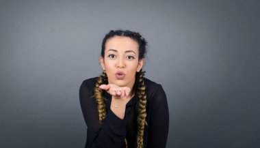 Sevimli bir kadın kameraya yumruk atar, sevgilisine aşkını gösterir ya da uzaktan veda eder, gri stüdyo arka planında izole bir şekilde.. 