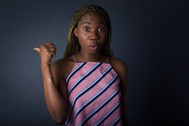 Genç Afro-Amerikan kadının gri arka plan noktalarının üzerinden yatay olarak çekilmiş fotoğrafı boş duvarda bir şey olduğunu gösteriyor.