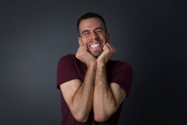 Genç, sevimli Avrupalı öğrencinin portresi duygularla dolup taşıyor. Heyecanı ve mutluluğu gözleri kapalı ve elleri kapalı ifade ederken gri arka planda geniş bir gülümsemeyle ifade ediyor..