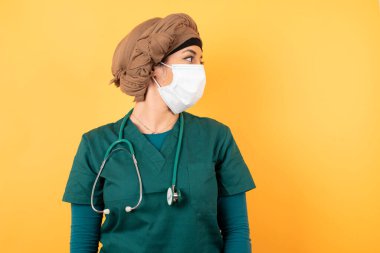 Yeşil üniformalı güzel Müslüman kadın profili. Beyaz stüdyo duvarında kopyalanmış..