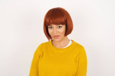 Güzel, melez, genç bir kadın modelin, kameraya sevimli bir gülümsemeyle bakarken içeriğiniz için beyaz, boş bir fotokopi duvarına poz verirken yakın çekimini yapın.