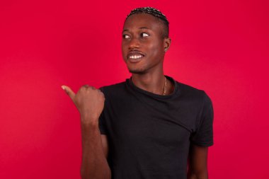 Omg konsepti. Şaşırmış Afro-Amerikan bir adam, şaşırmış bir ifadeyle, gözlerini ve ağzını iyice açıyor, başparmağıyla işaret ediyor, arka planda garip bir şey gösteriyor. Reklam kavramı.