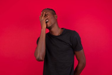Karizmatik, kaygısız, neşeli, arkadaş canlısı, siyah tişörtlü, kırmızı arka planda olan Afro-Amerikan erkeği.
