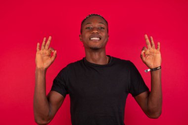 Çekici bir erkeğin iki eliyle işaret dili göstermesi sevindirici bir ifade, iyimser bir ifade. Duvara yaslanarak.