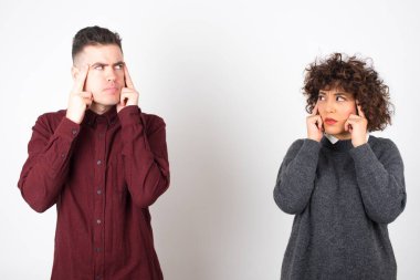  Düşünceli ifadeli sıradan kıyafetler giyen çift, gözlerini kaçırıyor, yüzlerine bakmıyor, hoş bir şeyler düşünüyor, gri duvara karşı poz veriyor..