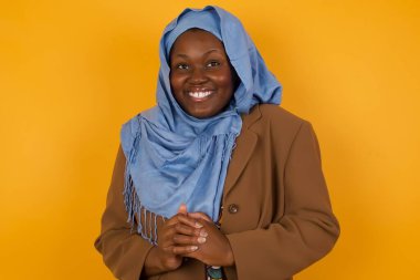 Vay canına. Sarı stüdyo arka planında izole edilmiş güzel yarı boy kadın portresi. Genç, duygusal olarak şaşırmış, ağzı açık, Afro-Amerikan Müslüman kadın. İnsani duygular, yüz ifadesi kavramı. Moda renkleri.